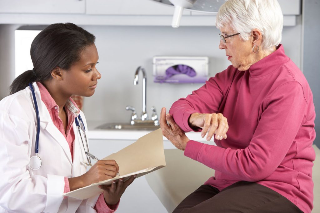 senior woman at hospital speaking to a doctor about her elbow and arm