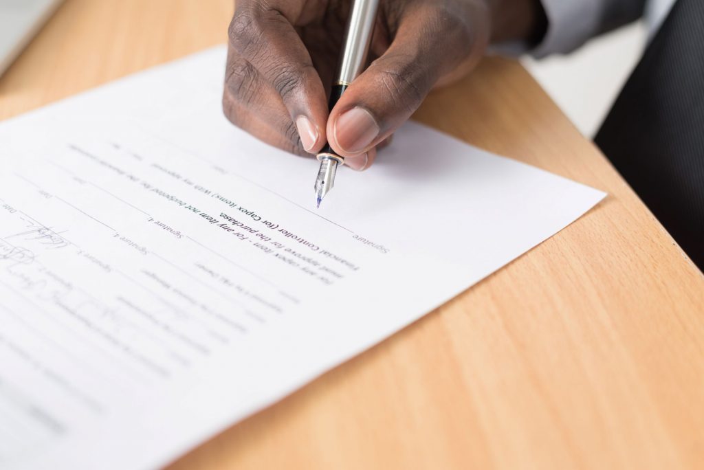 man signing a paper contract