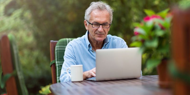 retirement man working outside on a laptop