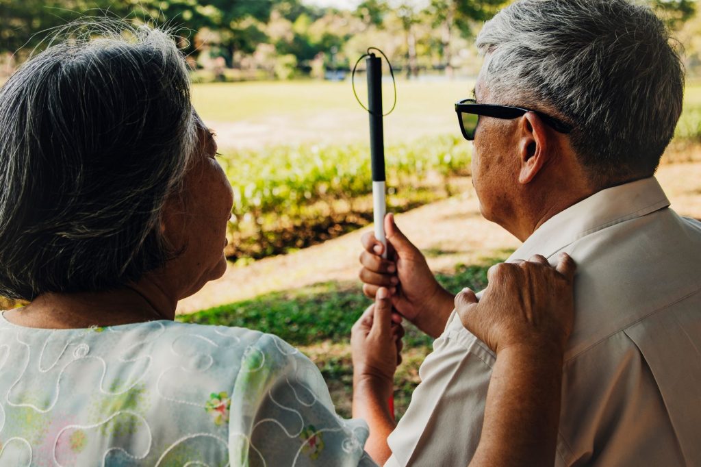 blind senior man and wife sitting next to him