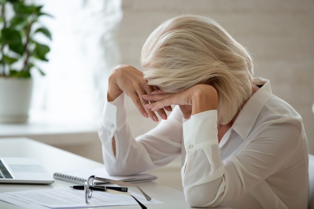 older lady slumped at desk stressed