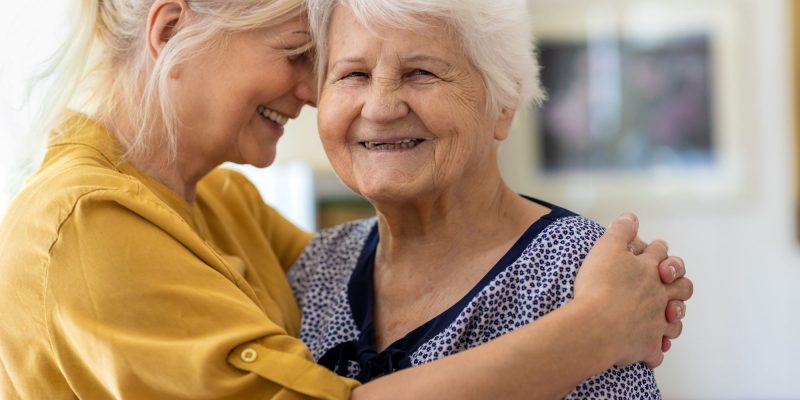hugging and smiling woman with senior mom