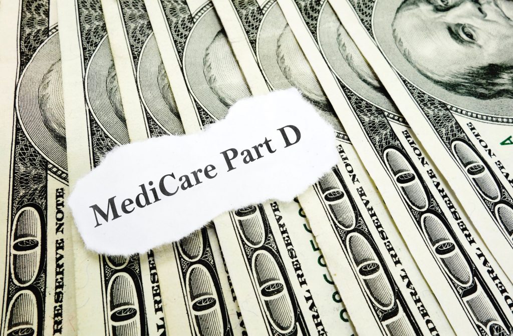 Medicare Part D in front of hundred dollar bills