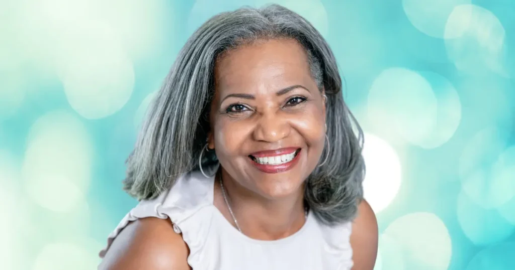 black senior woman with thin hair, short hair, teal background