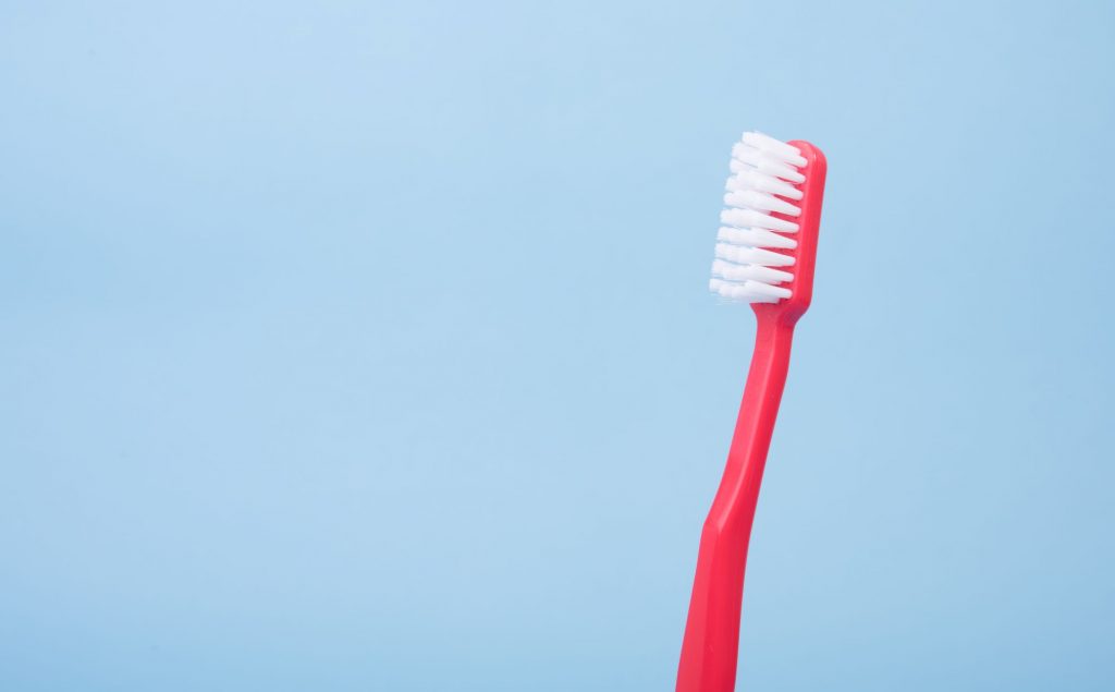 Red toothbrush on a blue background. For an article about dental care importance and Medicare coverage on SeniorResource.com