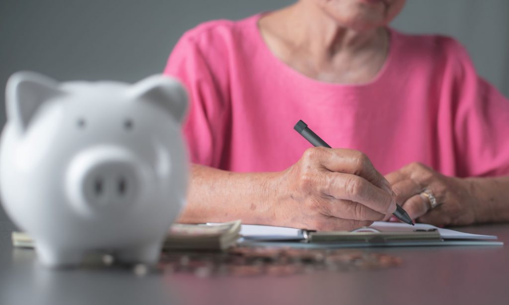 piggy bank and senior woman writing
