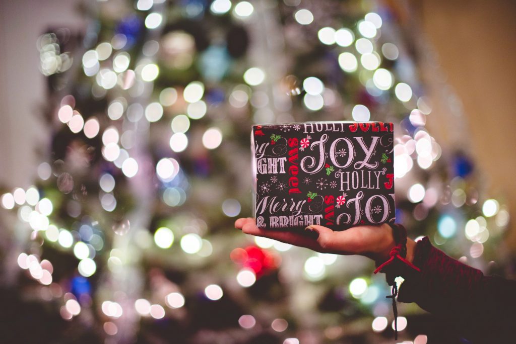 hand holding a gift in front of a tree