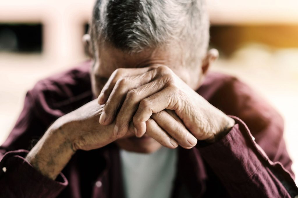 senior man upset with hands over face