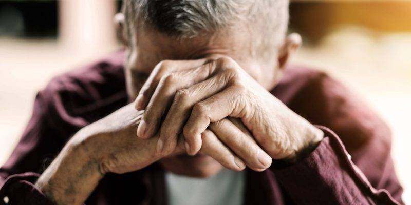 senior man upset with hands over face
