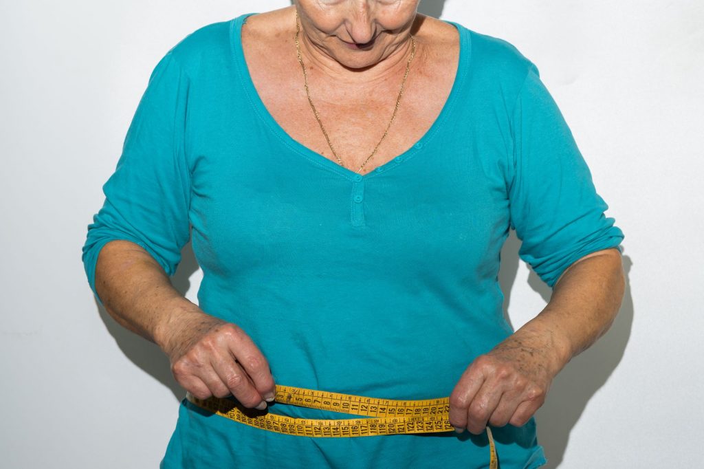 senior woman measuring waist, weight-loss concept
