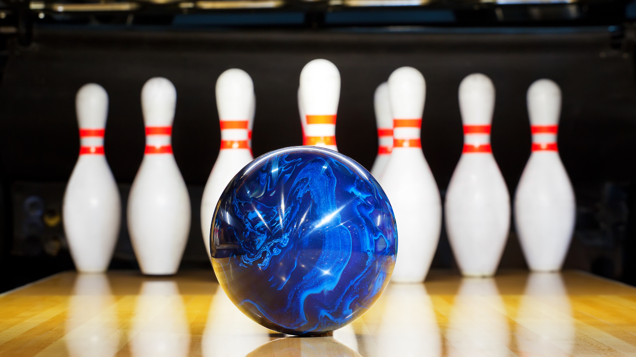 blue bowling ball headed toward bowling pins