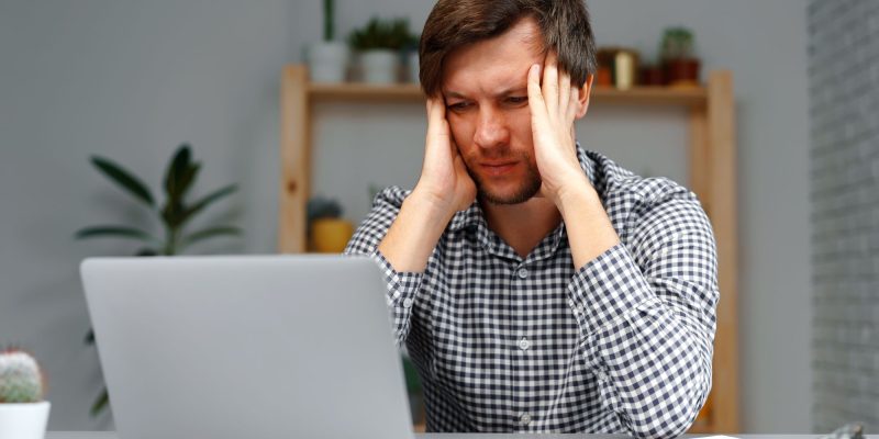 distressed man in front of computer holding head