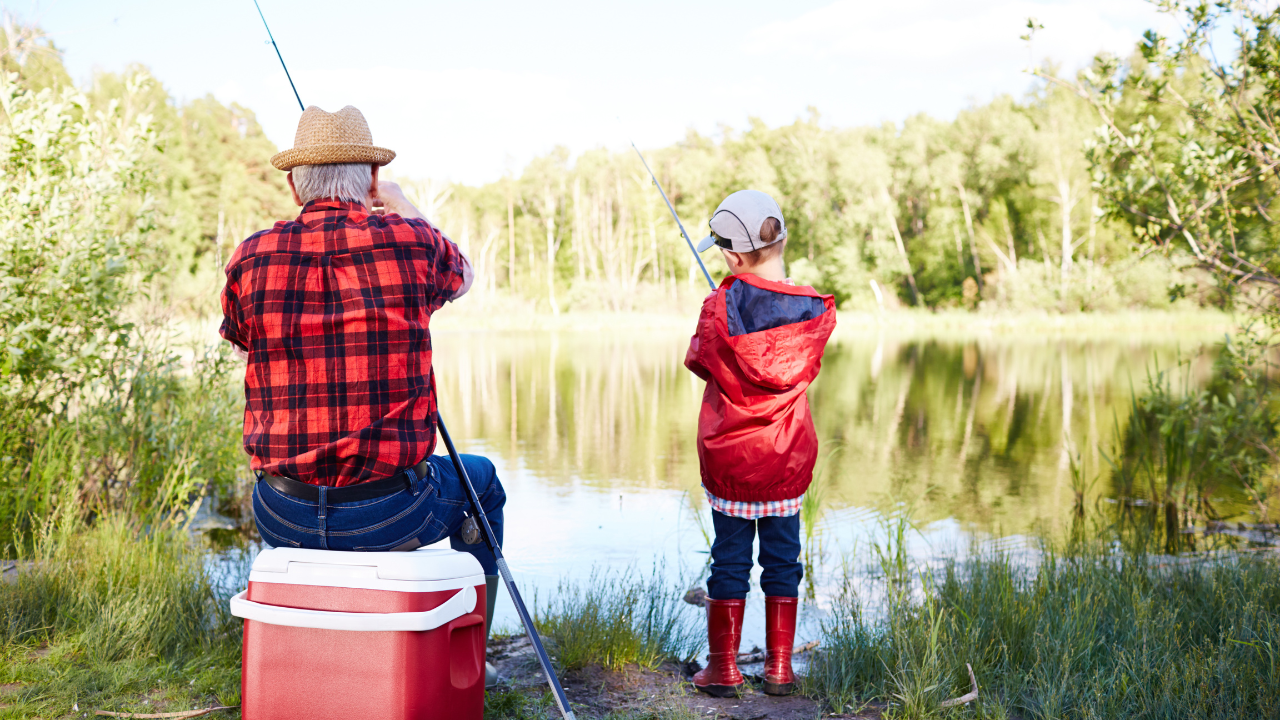 grandfather and grandson fishing on a small lake from the shore