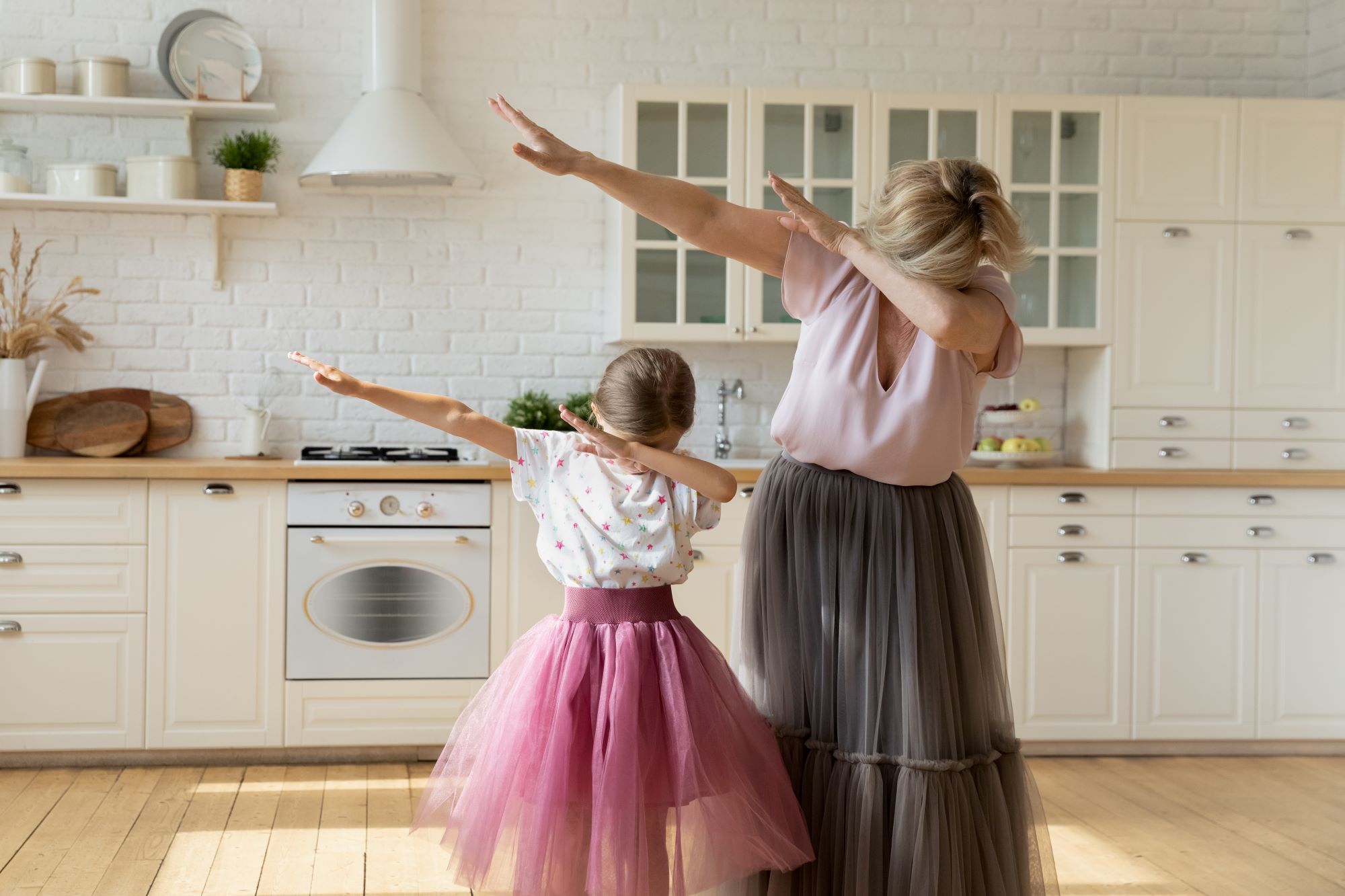 grandmother and granddaughter wearing tutus in the kitchen and dabbing