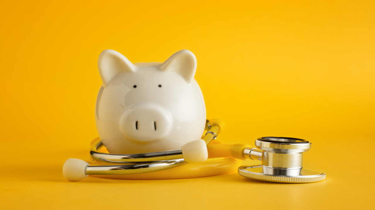 piggy bank with stethescope wrapped around on a yellow background