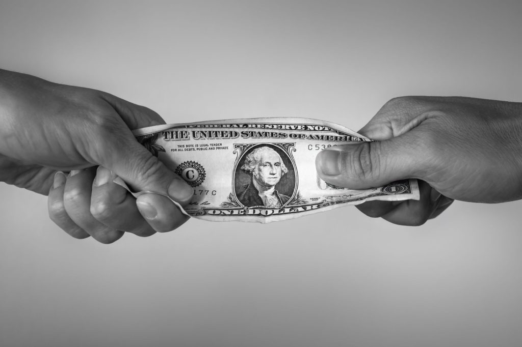 dollar bill with hands fighting ovver it