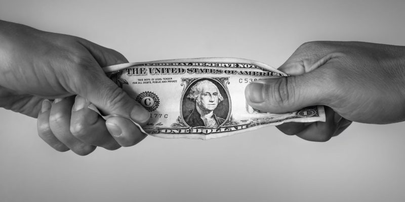 dollar bill with hands fighting ovver it
