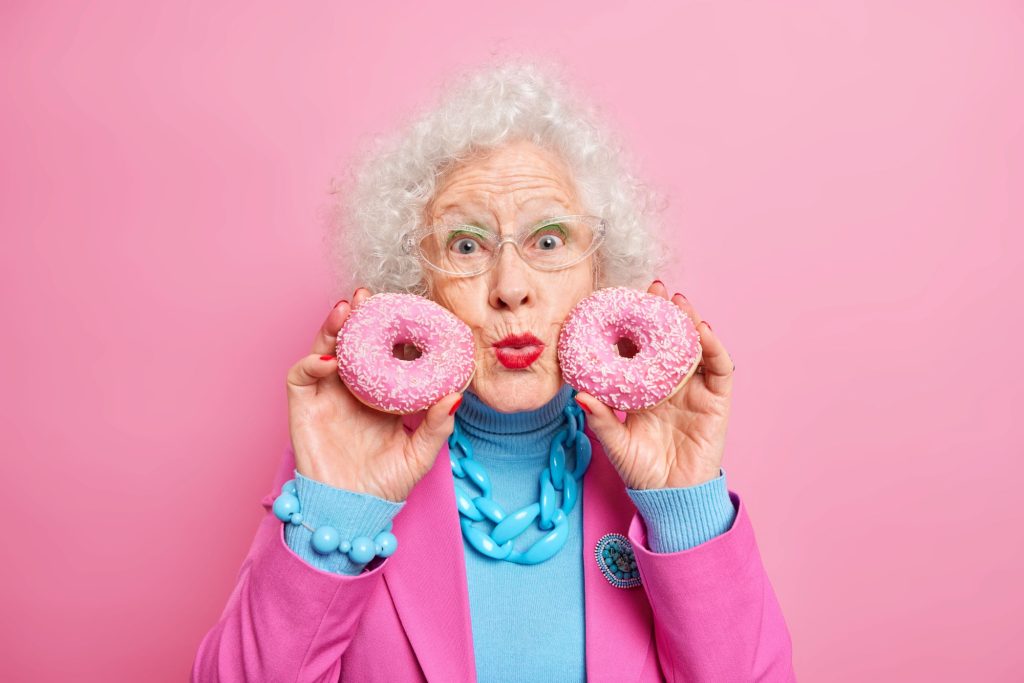 older adult with pink doughnuts