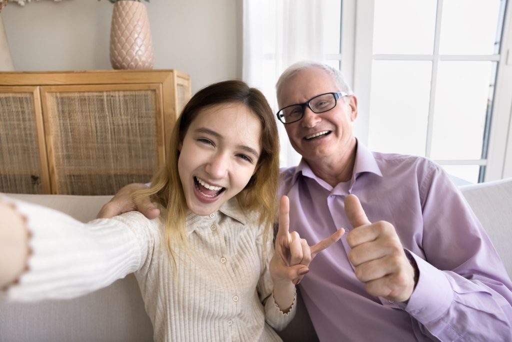 teen grandchild and grandfather taking a happy selfie together
