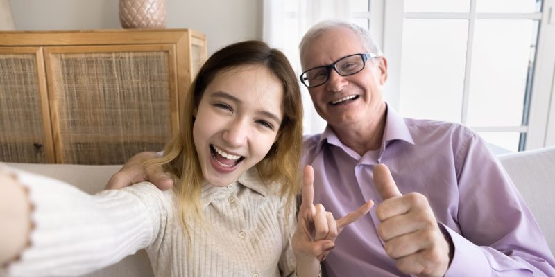 teen grandchild and grandfather taking a happy selfie together