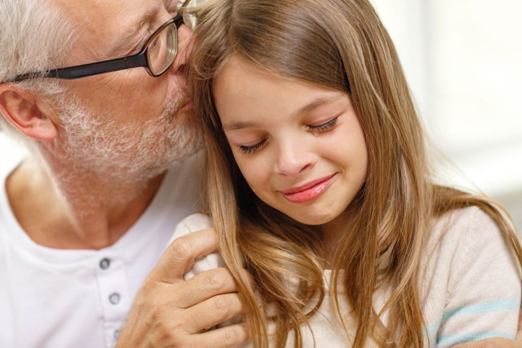 family, support, childhood and people concept - grandfather with crying granddaughter at home