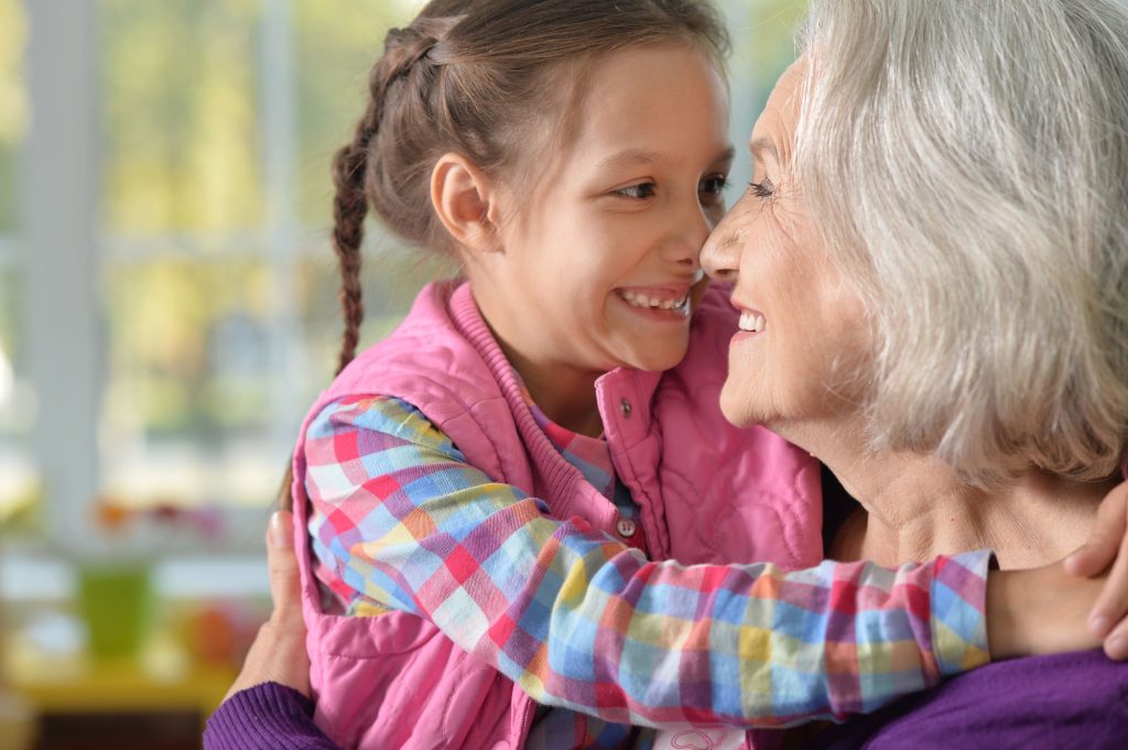 grandmother and granddaughter smiling at each other nose to nose