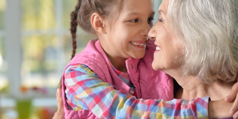 grandmother and granddaughter smiling at each other nose to nose
