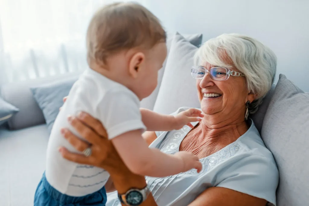 Proud grandmother playing with grandson. Woman with baby grandson