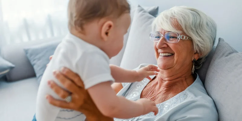 Proud grandmother playing with grandson. Woman with baby grandson