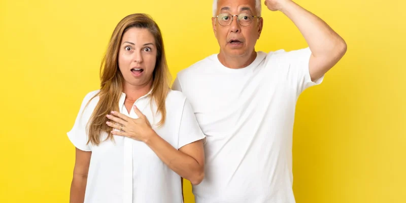 Middle age couple isolated on yellow background with surprise facial expression