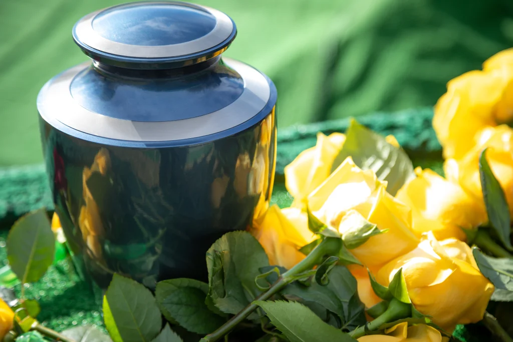 Close up on a burial urn with yellow roses, in a bright funeral scene