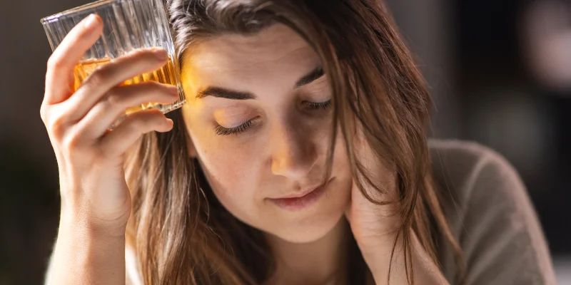 alcoholism, alcohol addiction and people concept - drunk woman or female alcoholic drinking whiskey at home