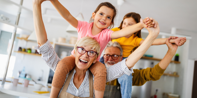 young grandparents with grandchildren on shoulders laughing