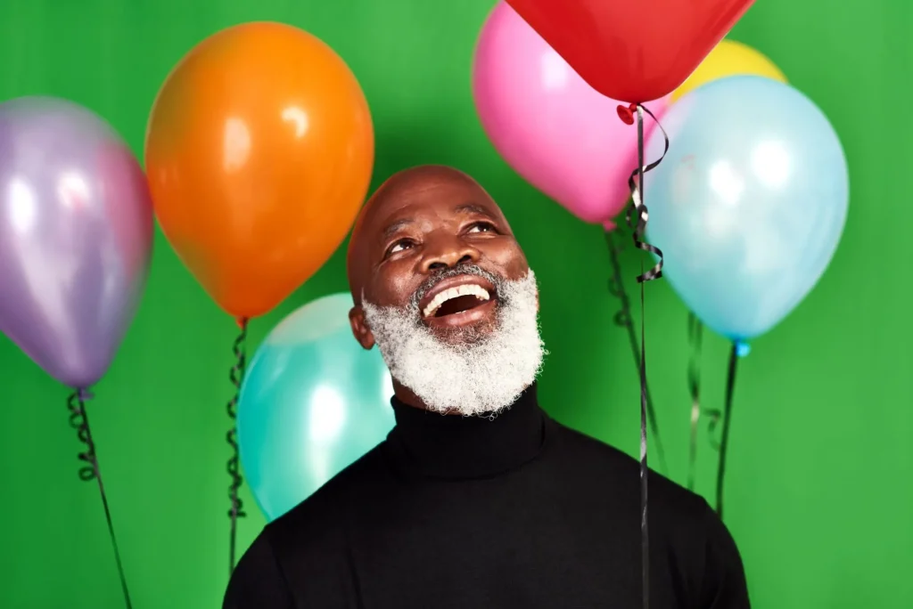Live your life and be merry. Studio shot of a man posing against a green background with balloons around him.