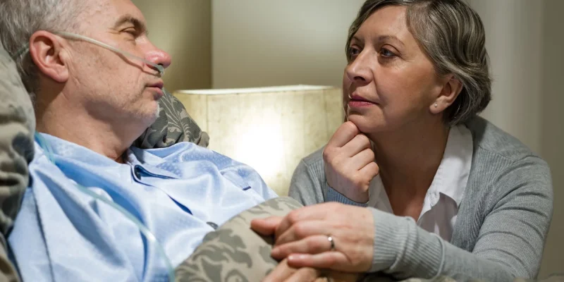 Senior patient at hospital with worried wife holding hands