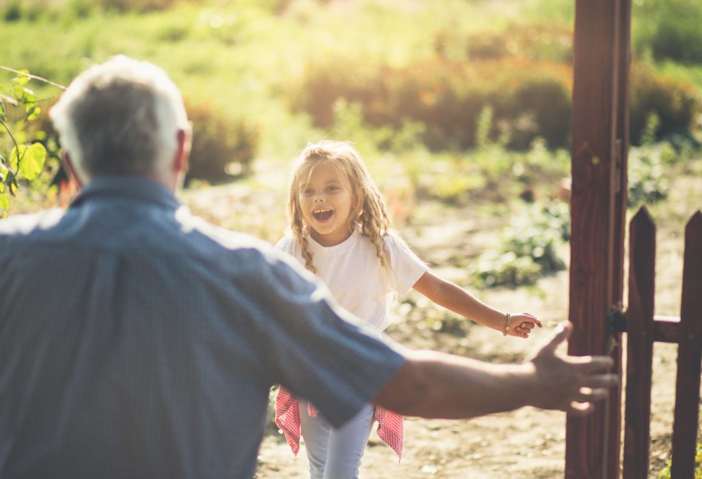 Granddaughter running in hug to her grandfather. Close up. Copy space. Focus on little girl.