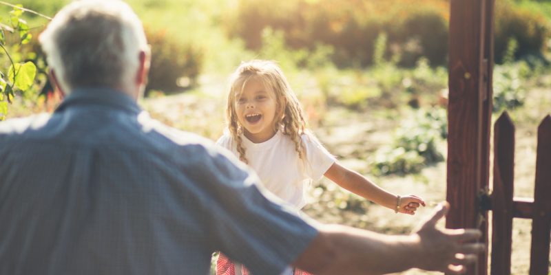 Granddaughter running in hug to her grandfather. Close up. Copy space. Focus on little girl.