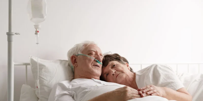 Shot of a sad wife lying next to sick husband at the hospital