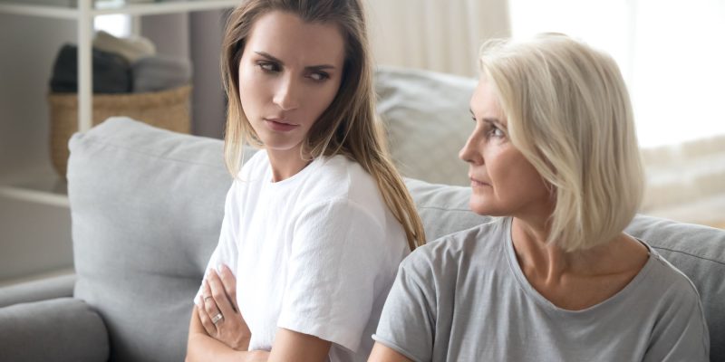 Angry aged mother and daughter looking at each other after quarrel, bad family relationships concept, parent and child conflict, different age generations, stubborn displeased women with arms crossed