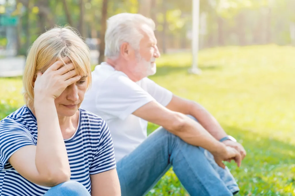 senior couple sitting outisde, arguing with one another, not speaking