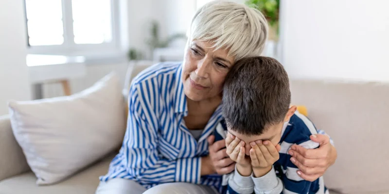 Loving understanding old grandma embracing little crying boy comforting upset grandson, senior caring grandmother hugging child consoling kid in tears, grannys empathy support for grandchild