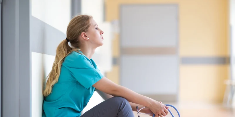 Tired female nurse in hospital corridor