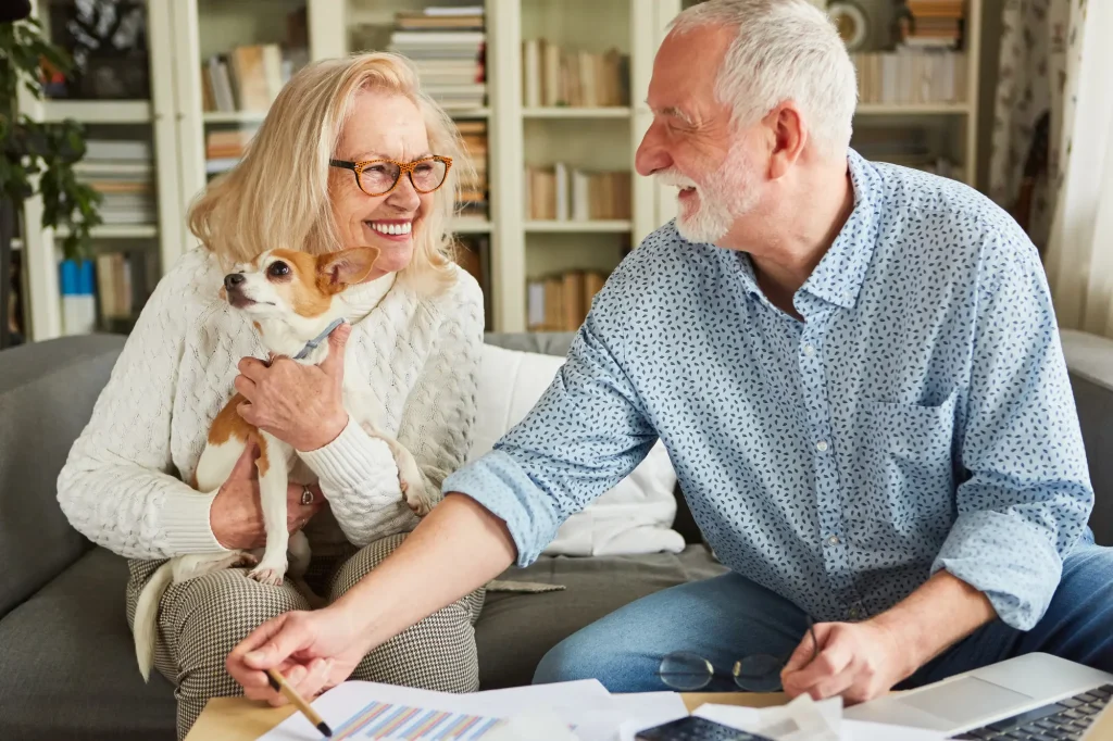 two seniors with tax info on coffee table sitting on couch with dog in lap