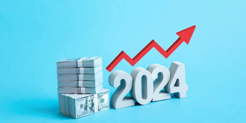 2024 costs that keep rising, concept on a blue background, red arrow pointing up with dollar bills
