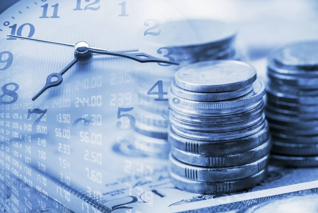 annuity clock, Closeup view : Stack of coins and a clock hands. A concept / idea of time value of money. Money at present time is worth more than the same amount in the future due to its potential earning capacit