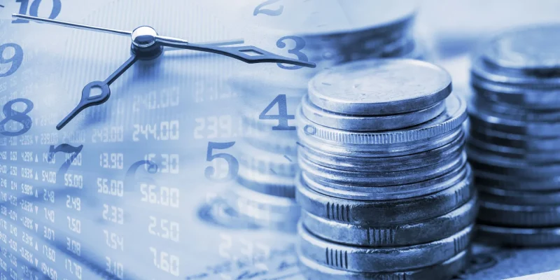 annuity clock, Closeup view : Stack of coins and a clock hands. A concept / idea of time value of money. Money at present time is worth more than the same amount in the future due to its potential earning capacit