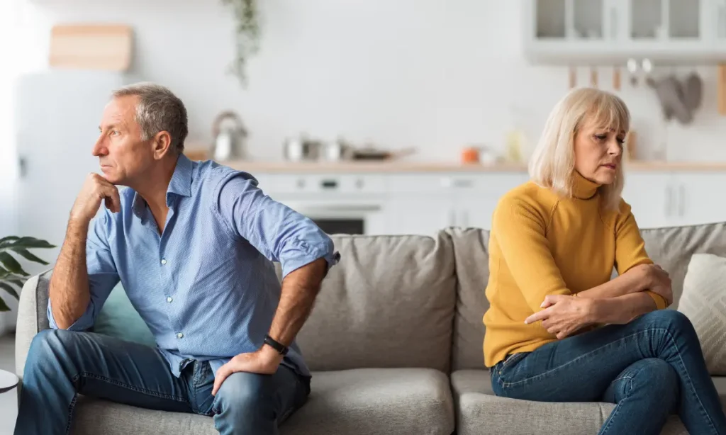 arguing young retired couple, sitting on the couch, not speaking to one another