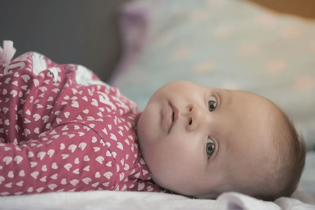 close up of baby laying on back in crib