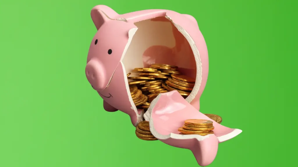 broken piggy bank on a green background, coins on the inside of the piggy bank