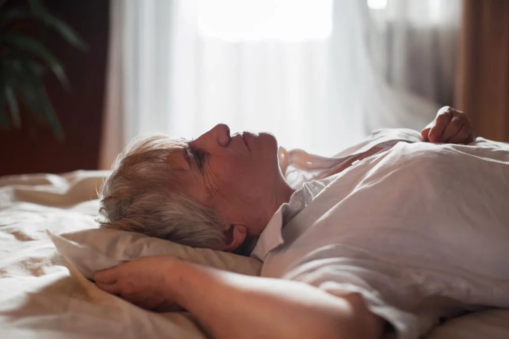 Middle aged mature woman insomniac lying awake in bed looking up trying to sleep, unhappy old senior lady feel disturbed frustrated suffer from insomnia concept uncomfortable bad mattress